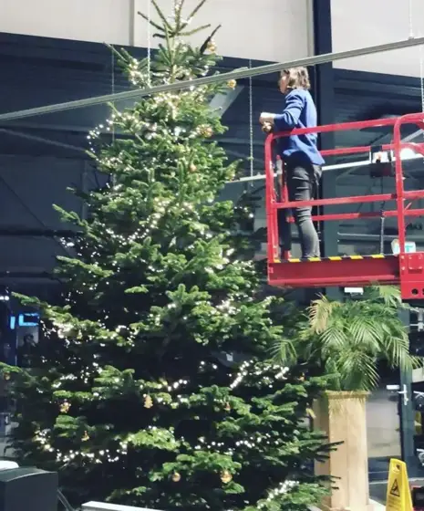 Grote kerstboom wordt vanaf een hoogwerker versierd bij Opel
