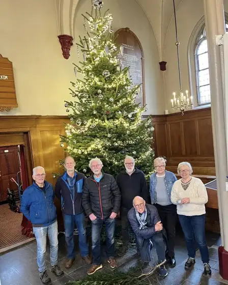 Vrijwilligers van de Pauluskerk in Baarn bij hun kerstboom van 4,5 meter