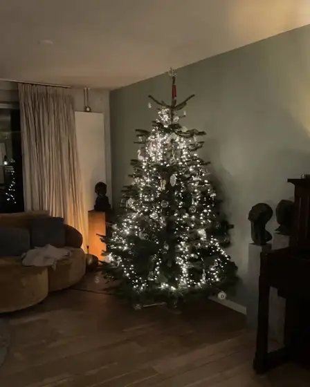 Verlichte kerstboom in een hoek van een woonkamer