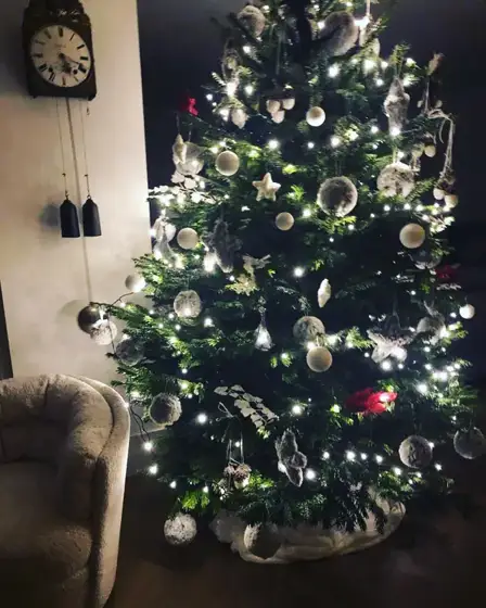 Kerstboom met witte pluizige ballen naast een stoel